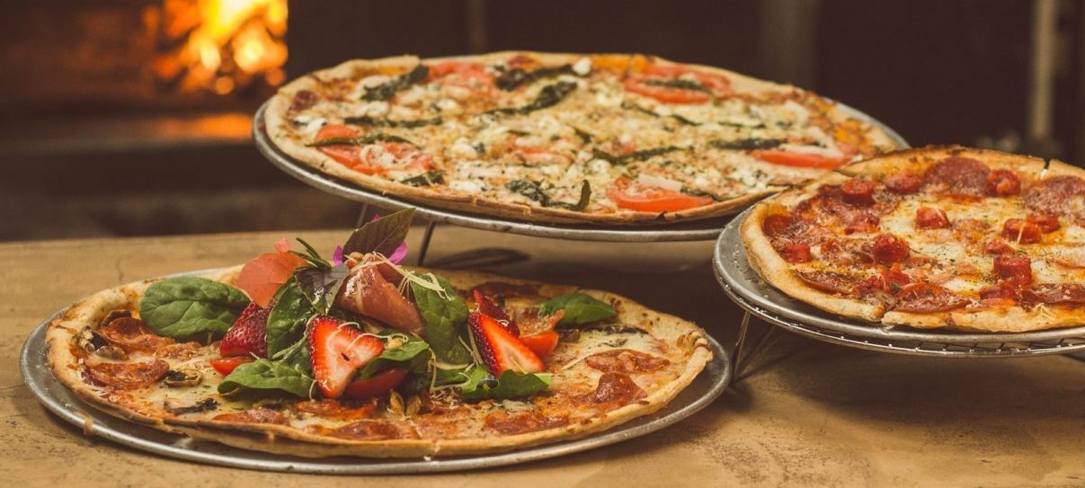 pizza with cheese and tomatoes on brown wooden round plate